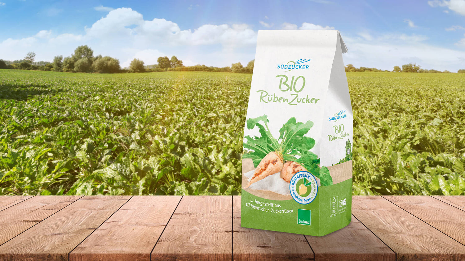 Packung Südzucker Bio Rübenzucker mit Zuckerrüben-Motiv, Bioland- und Herkunftssiegel vor einem Zuckerrübenfeld
